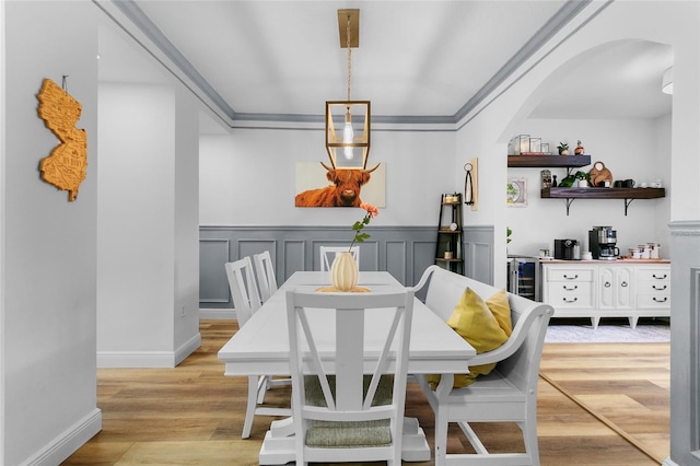 dining room with crown molding, light wood-type flooring, and beverage cooler