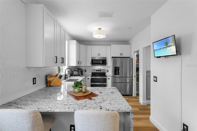 kitchen with white cabinetry, decorative backsplash, sink, stainless steel appliances, and light stone counters