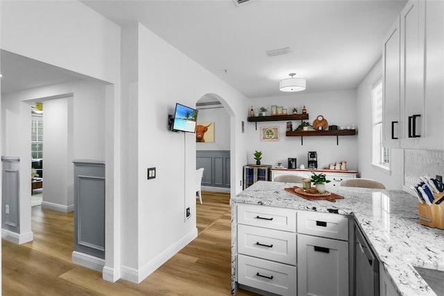 bar with white cabinetry, light stone counters, and light hardwood / wood-style floors