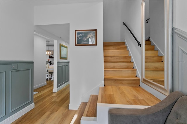 staircase with hardwood / wood-style floors and a chandelier