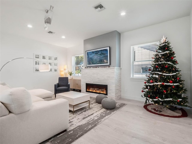 living room with a tile fireplace and light hardwood / wood-style flooring