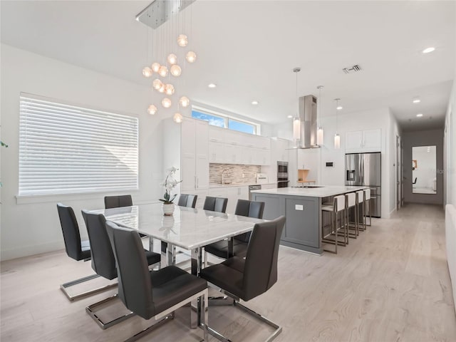 dining area featuring light wood-type flooring, sink, and an inviting chandelier