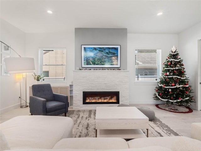 living room with light hardwood / wood-style floors, a wealth of natural light, and a stone fireplace