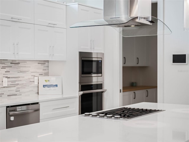 kitchen featuring ventilation hood, stainless steel appliances, backsplash, and white cabinetry