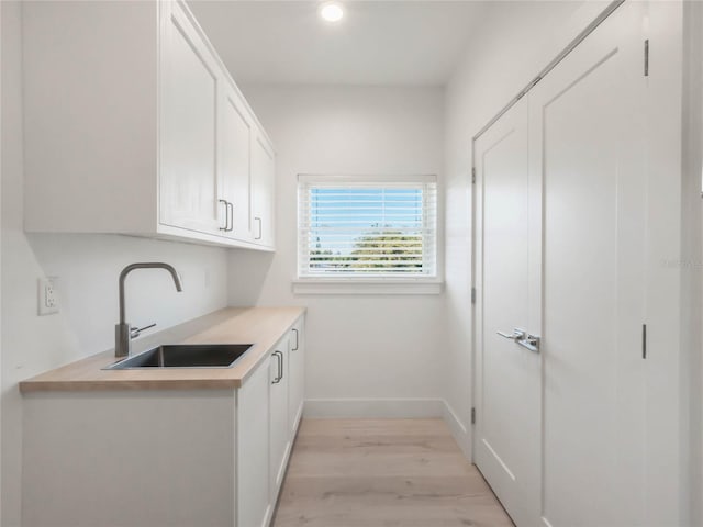 kitchen with white cabinetry, light hardwood / wood-style flooring, and sink