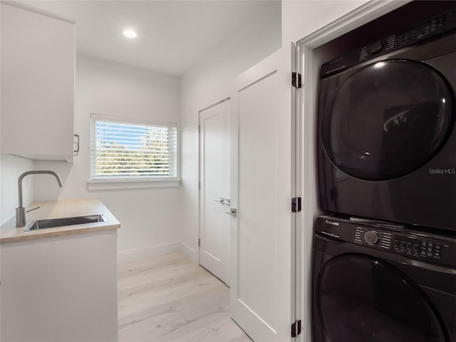 washroom with stacked washer / drying machine, sink, and light hardwood / wood-style floors