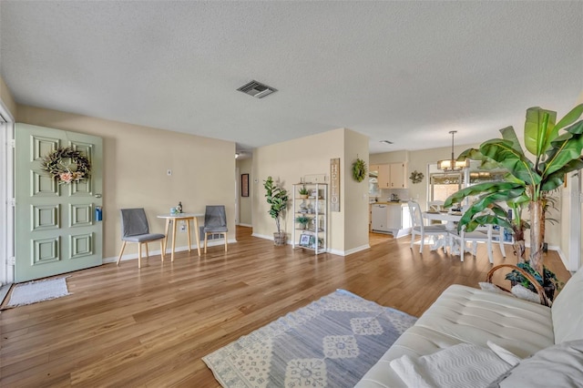 living room featuring a chandelier, light hardwood / wood-style floors, and a textured ceiling