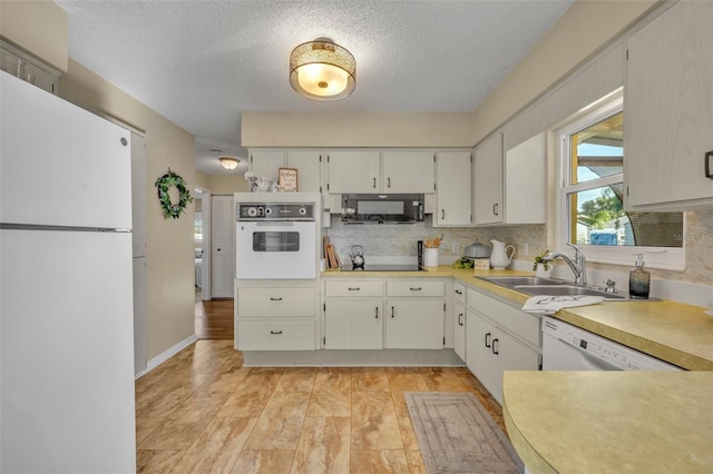 kitchen with sink, backsplash, white cabinets, white appliances, and a textured ceiling