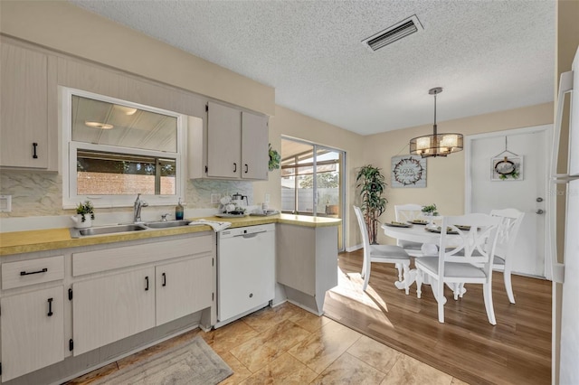 kitchen with a healthy amount of sunlight, white dishwasher, sink, and hanging light fixtures