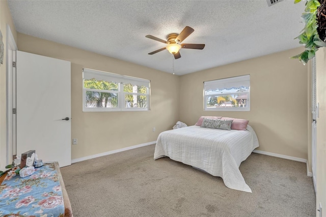 bedroom with ceiling fan, light carpet, and a textured ceiling