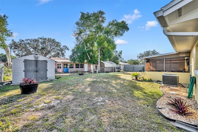 view of yard featuring central AC unit, a sunroom, and a storage unit