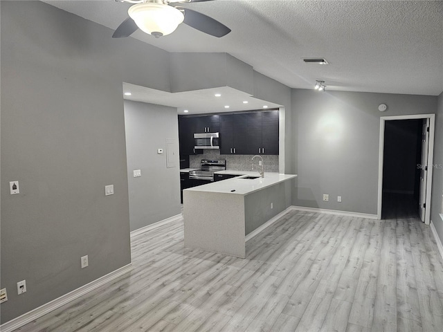 kitchen featuring ceiling fan, kitchen peninsula, sink, appliances with stainless steel finishes, and a textured ceiling