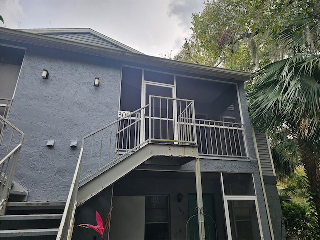 back of property with a balcony and stucco siding