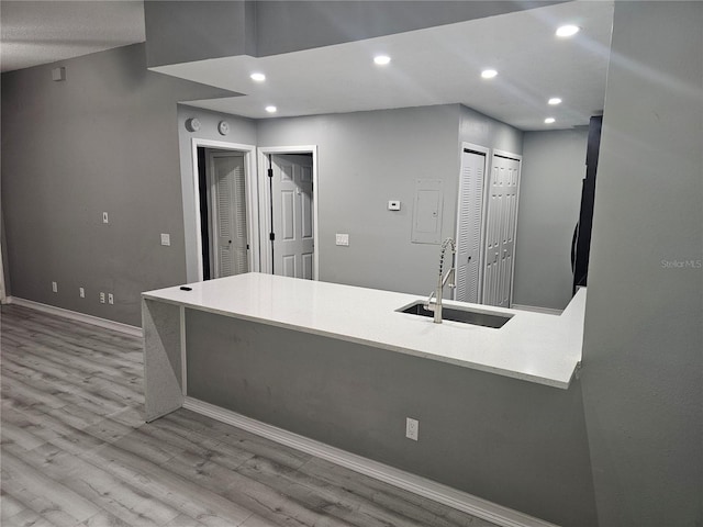 kitchen with recessed lighting, light countertops, a sink, light wood-type flooring, and baseboards