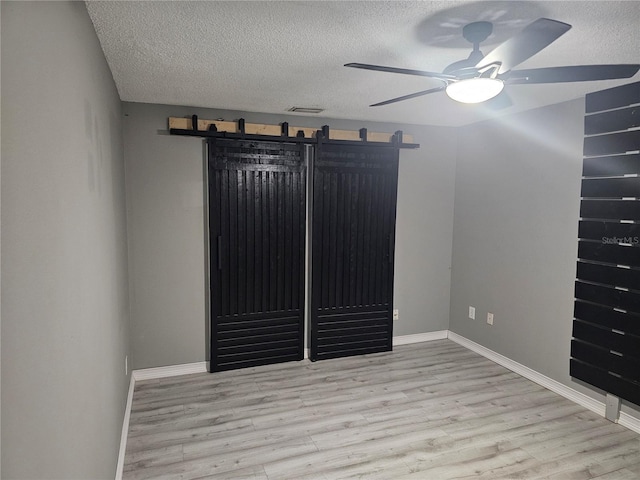 unfurnished room with ceiling fan, a textured ceiling, visible vents, and light wood-style floors