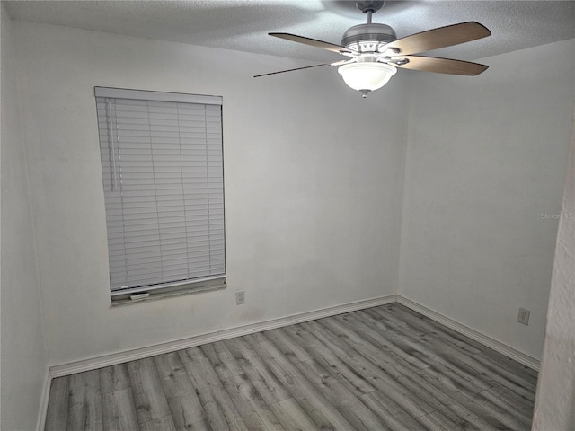 spare room with ceiling fan, a textured ceiling, baseboards, and wood finished floors