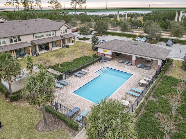 pool at dusk with a patio area and a yard