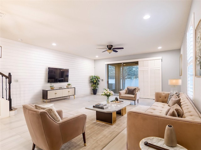 living room with ceiling fan and wood walls