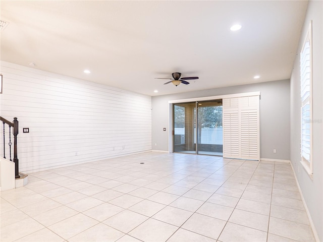 unfurnished room featuring ceiling fan, light tile patterned floors, wooden walls, and a healthy amount of sunlight