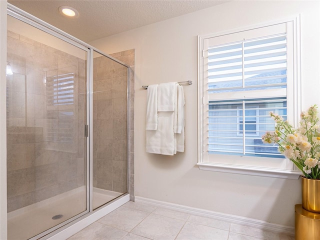 bathroom with a textured ceiling, tile patterned flooring, and an enclosed shower