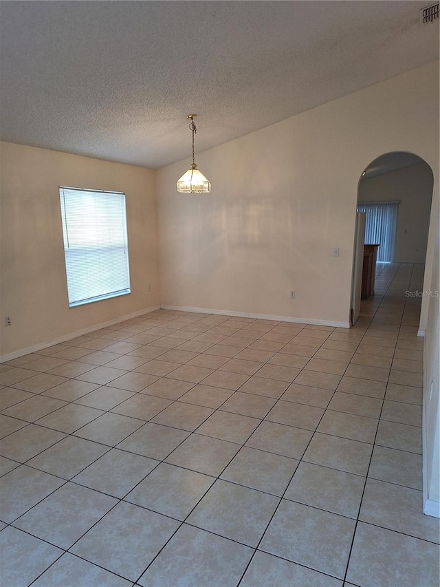 tiled spare room featuring a textured ceiling