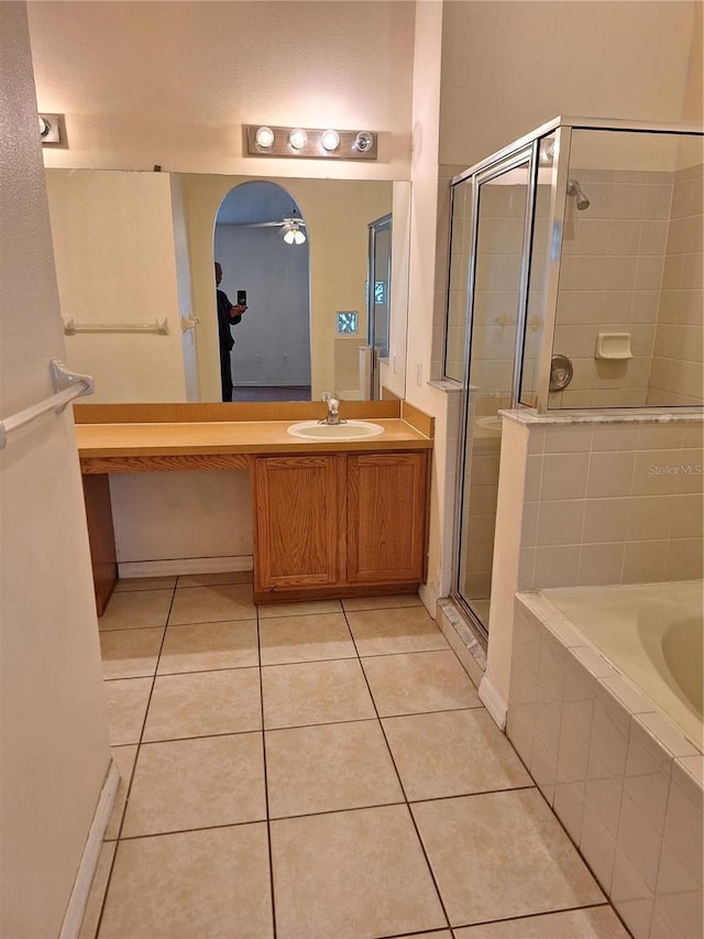 bathroom with plus walk in shower, tile patterned flooring, ceiling fan, and vanity