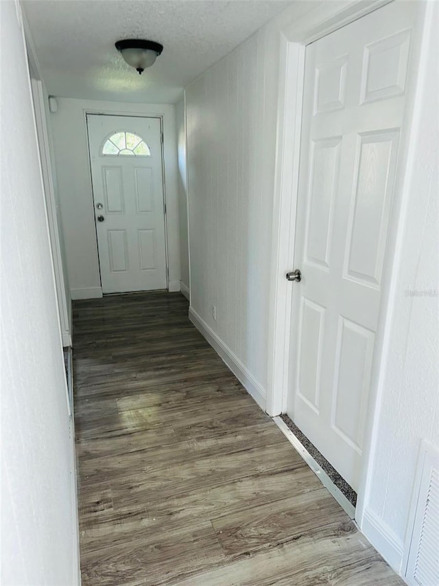 doorway featuring a textured ceiling and dark hardwood / wood-style floors