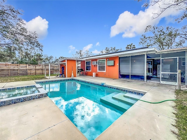 view of pool with a patio area, a sunroom, and an in ground hot tub