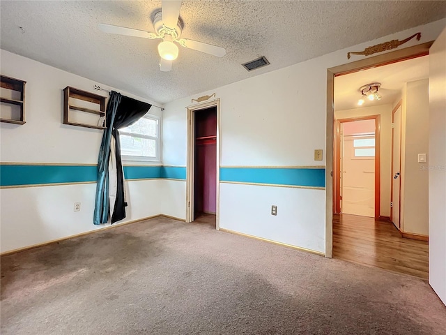 carpeted spare room featuring ceiling fan and a textured ceiling