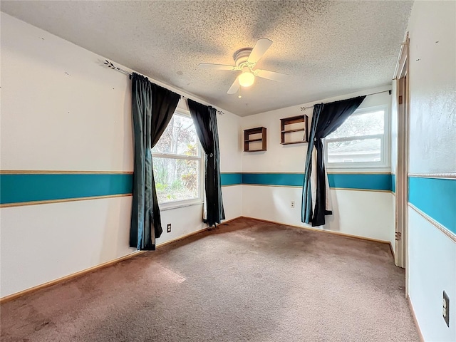 empty room featuring ceiling fan, a textured ceiling, and carpet flooring