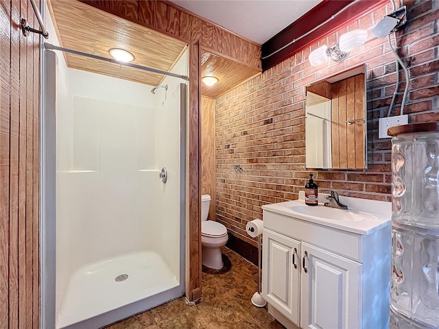 bathroom featuring walk in shower, vanity, brick wall, and toilet