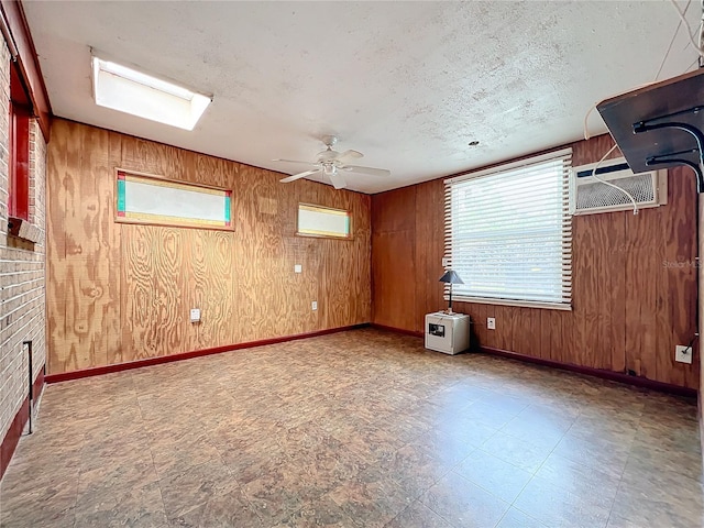 empty room featuring ceiling fan, wood walls, a textured ceiling, and a wall unit AC