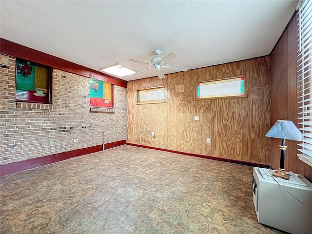 unfurnished room featuring ceiling fan, brick wall, and wood walls