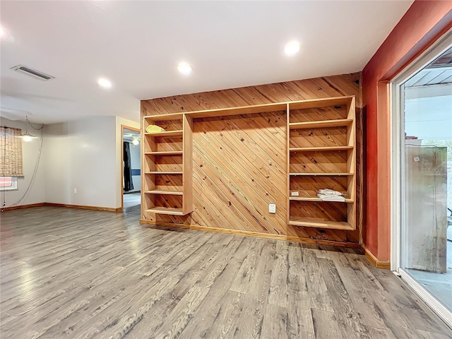 interior space featuring built in features, wood walls, and hardwood / wood-style flooring