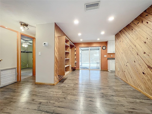 unfurnished living room with wood-type flooring and wood walls