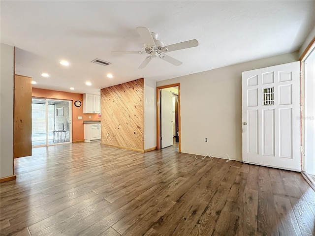 unfurnished living room featuring ceiling fan, wooden walls, and hardwood / wood-style floors