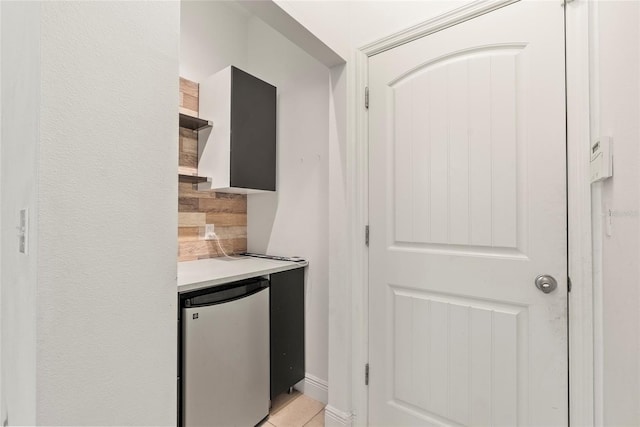 kitchen with light tile patterned floors and stainless steel fridge