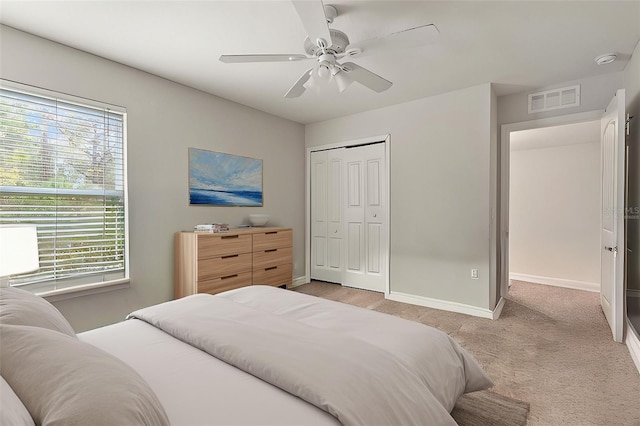 bedroom with ceiling fan, multiple windows, a closet, and light carpet