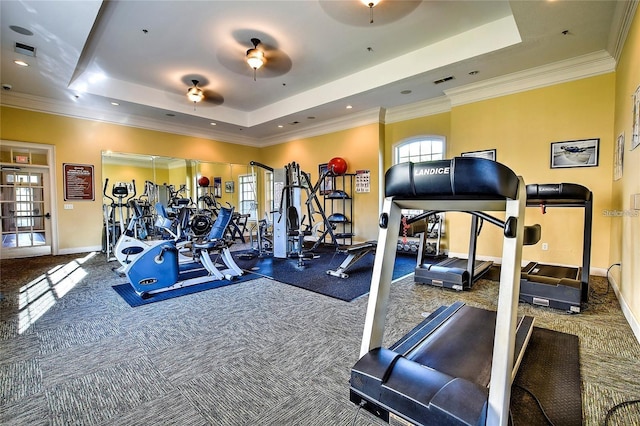 workout area featuring ceiling fan, carpet, ornamental molding, and a raised ceiling