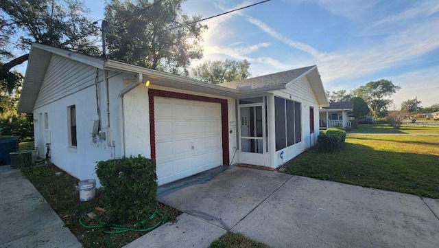 view of home's exterior with a garage, a sunroom, and a yard