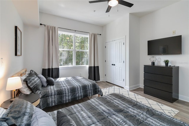 bedroom with ceiling fan, light hardwood / wood-style floors, and a closet