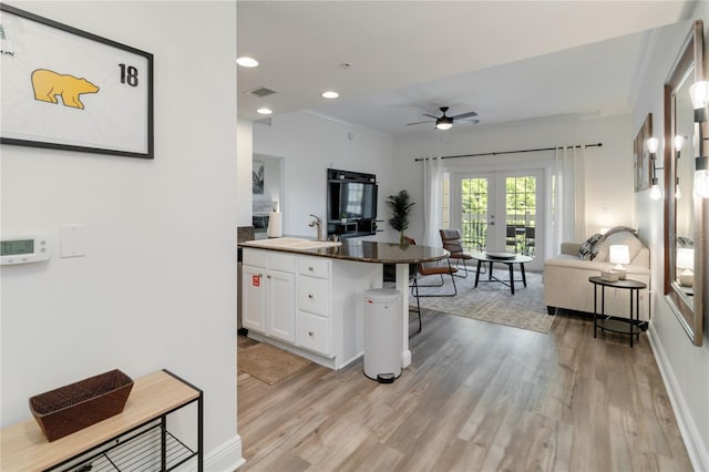 kitchen with white cabinetry, sink, a kitchen breakfast bar, light hardwood / wood-style floors, and french doors