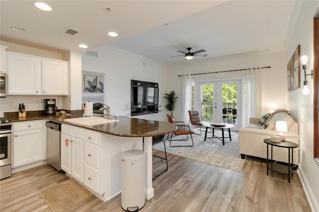 kitchen featuring sink, white cabinets, a kitchen bar, kitchen peninsula, and stainless steel appliances