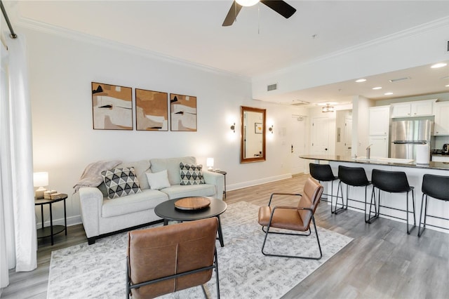 living room with ceiling fan, ornamental molding, and hardwood / wood-style floors