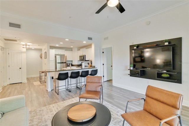 living room with light hardwood / wood-style flooring, ornamental molding, and ceiling fan