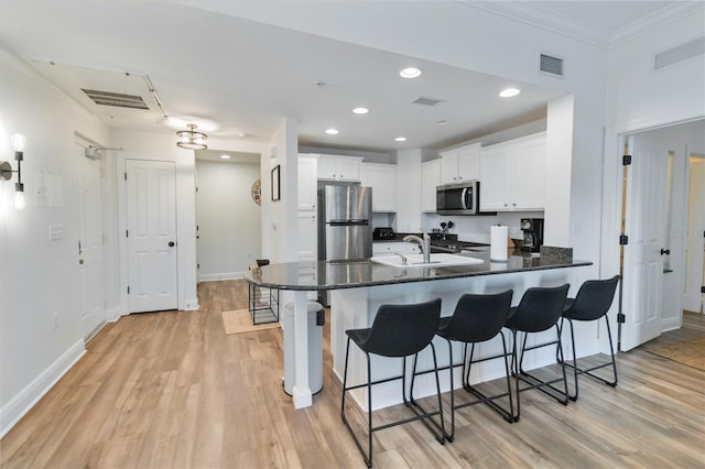 kitchen featuring sink, a breakfast bar area, appliances with stainless steel finishes, kitchen peninsula, and white cabinets