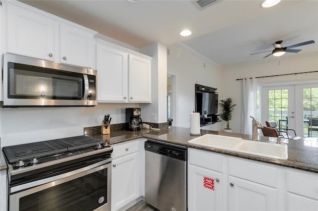 kitchen featuring appliances with stainless steel finishes, white cabinetry, sink, dark stone countertops, and crown molding