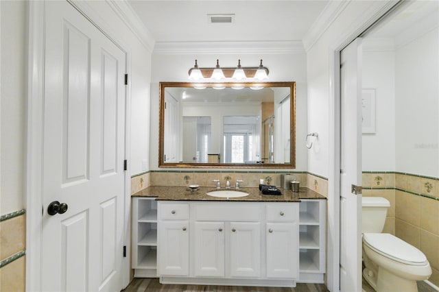 bathroom featuring tile walls, hardwood / wood-style flooring, ornamental molding, vanity, and toilet