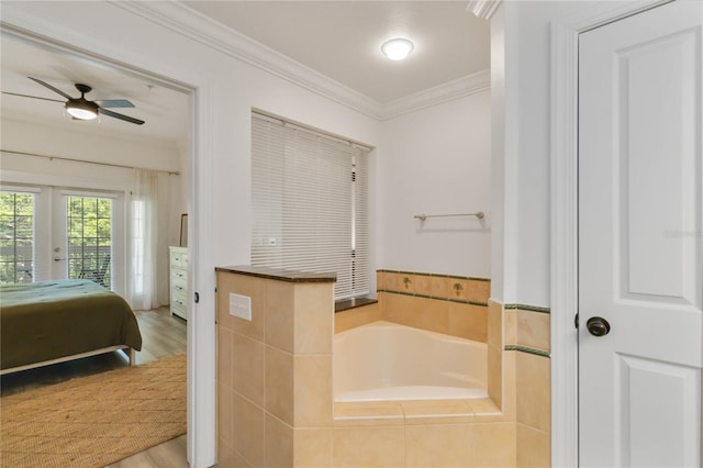 bathroom featuring tiled tub, hardwood / wood-style flooring, ornamental molding, and ceiling fan