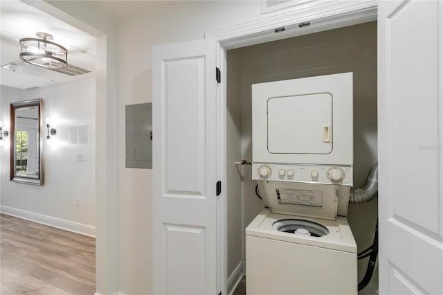 clothes washing area featuring stacked washer and dryer, electric panel, and light hardwood / wood-style floors